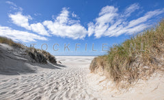 Strandopgang met wolkenlucht.